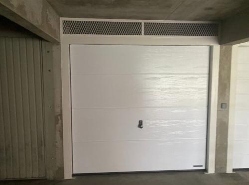 Installation-dune-porte-sectionnelle-HORMANN-avec-grille-de-metal-deploye-–-Coloris-Blanc-gris-RAL-9002-cote-ext-–-04-2024